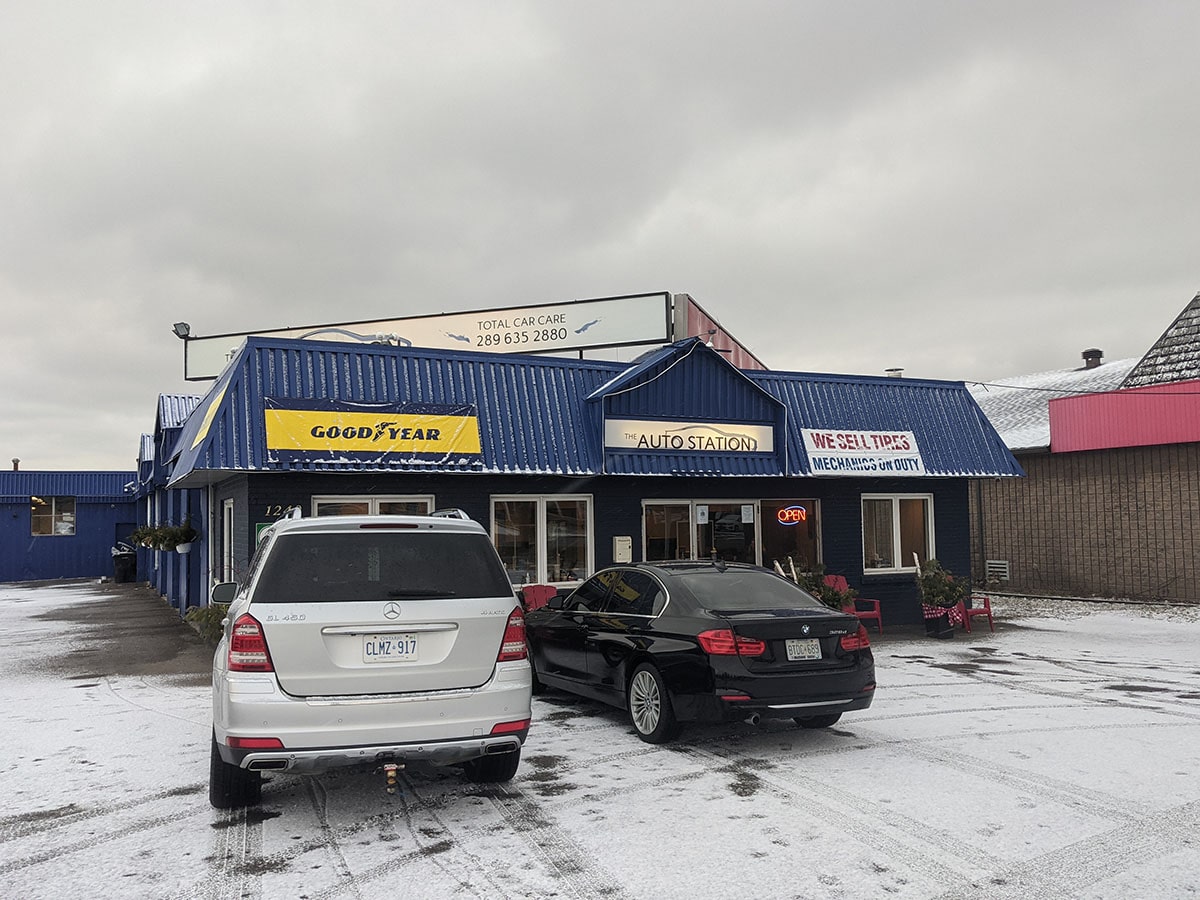 a BMW and Mercedes parked in a snowy Auto Station parking lot
